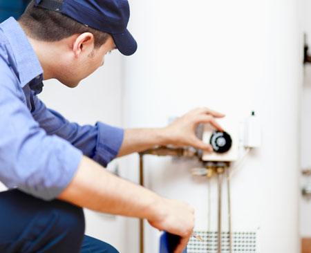 A tech checking the thermostat of a recent water heater installation and water heater flush appointment