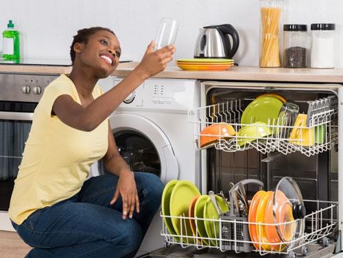 A woman holding a clean glass that recently went through the dish washer