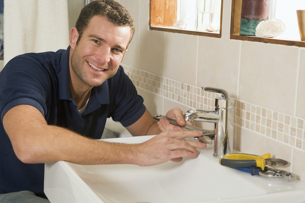 best plumber salt lake city working on sink while smiling